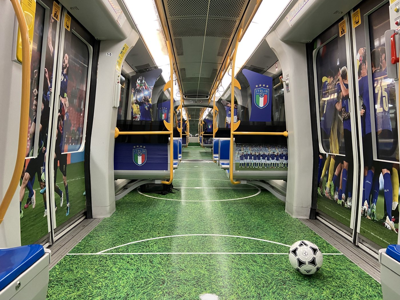 Treno M5 vestito interamente per la Nazionale Italiana di calcio FIGC — pavimento prato, pallone, foto degli azzurri